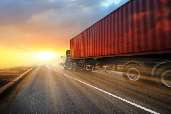 Generic big trucks speeding on the highway at sunset - Transport industry concept , big truck containers