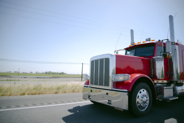 Big rig classic red semi truck with a lot of chrome details on this custom built car for show individual style of driver for everybody who drive on this road in common traffic