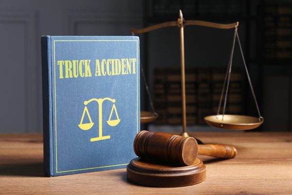 Truck accident law book with gavel and justice scale on wooden desk