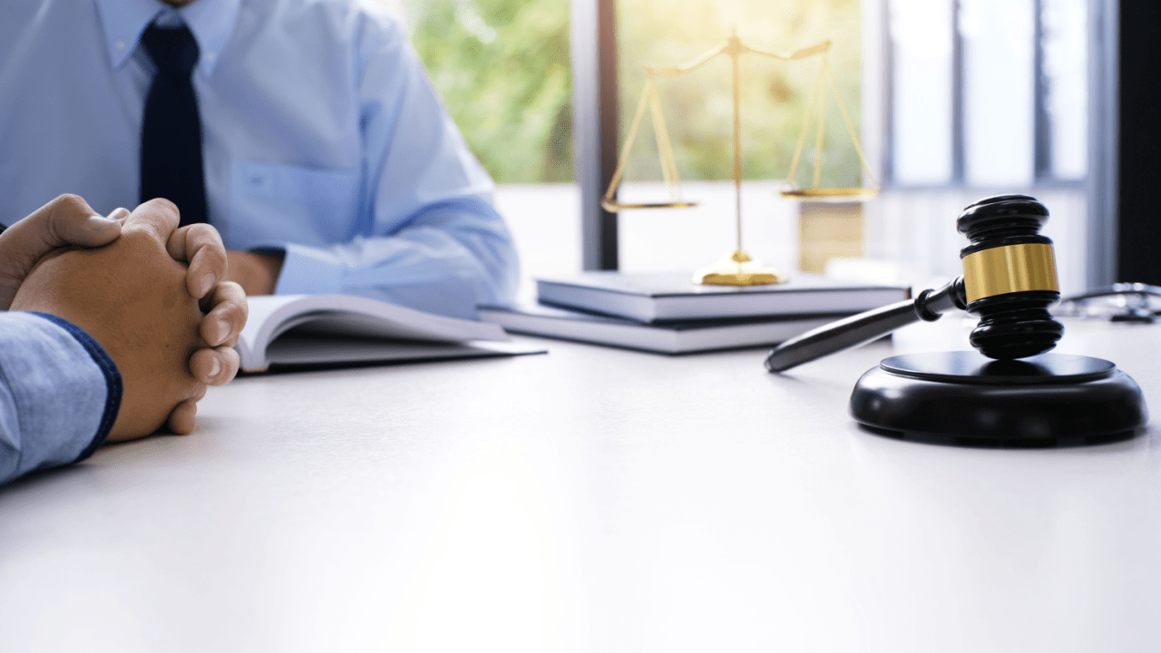 A truck accident attorney and injured client discuss a claim summary in a small-town law office with a truck passing outside the window.