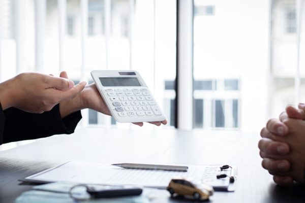 An insurance agent showing legal costs on a calculator during a client meeting