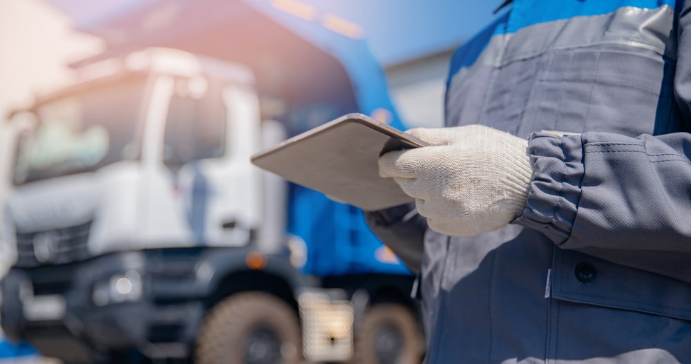 Truck inspector holding a tablet in front of a commercial vehicle