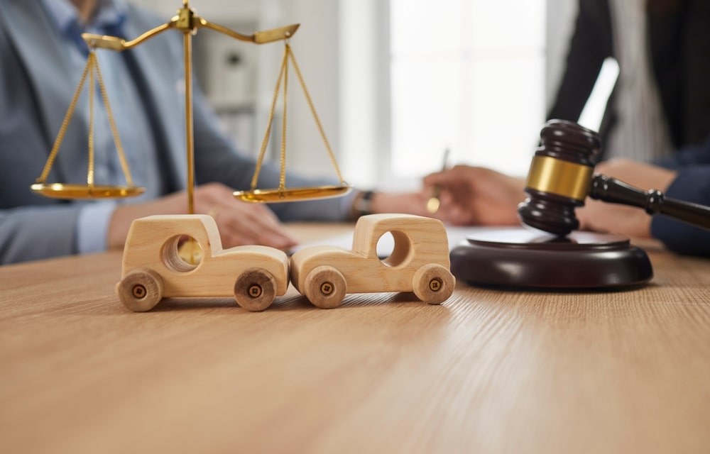 Wooden toy cars with a gavel and a justice scale in the background during legal consultation
