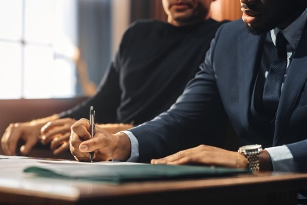 Lawyer writing notes while the client sits beside him