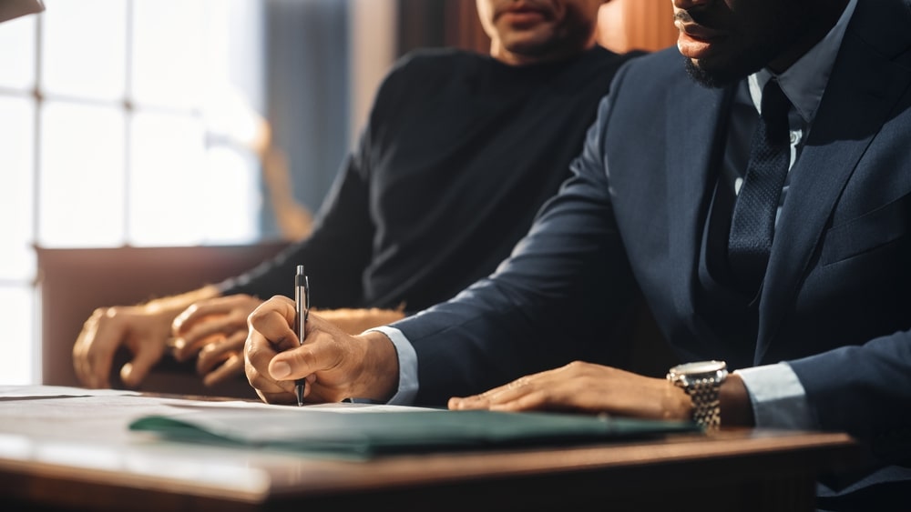 Lawyer writing notes while the client sits beside him