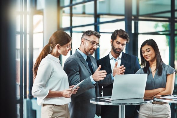 A group of insurance professionals and lawyers reviewing a legal strategy on a laptop