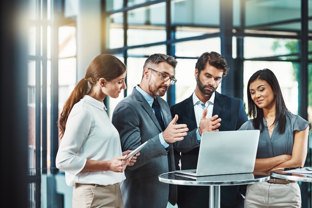 A group of insurance professionals and lawyers reviewing a legal strategy on a laptop