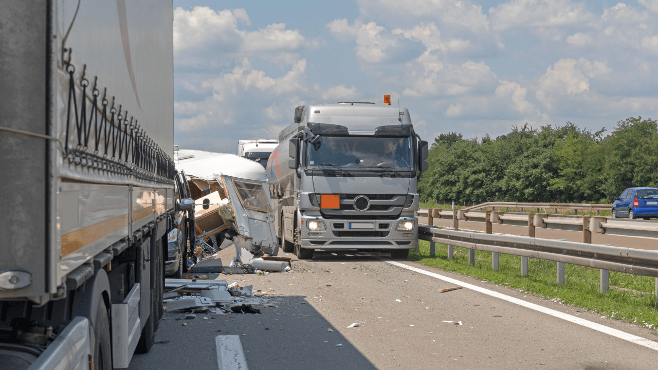 Multi-vehicle traffic accident on highway with damaged truck, RV, and debris scattered across roadway