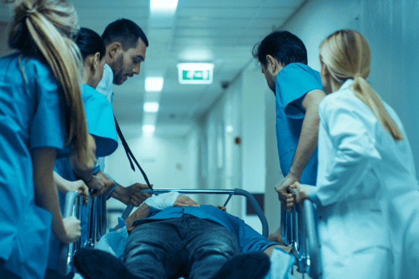 Medical team in scrubs rushing patient on gurney through hospital corridor in emergency situation