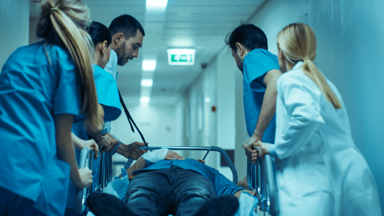 Medical team in scrubs rushing patient on gurney through hospital corridor in emergency situation
