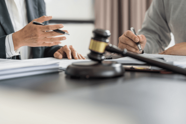 Lawyer consulting with client over legal documents with gavel on desk in professional office setting