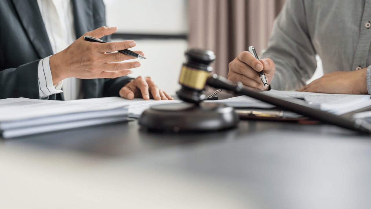 Lawyer consulting with client over legal documents with gavel on desk in professional office setting