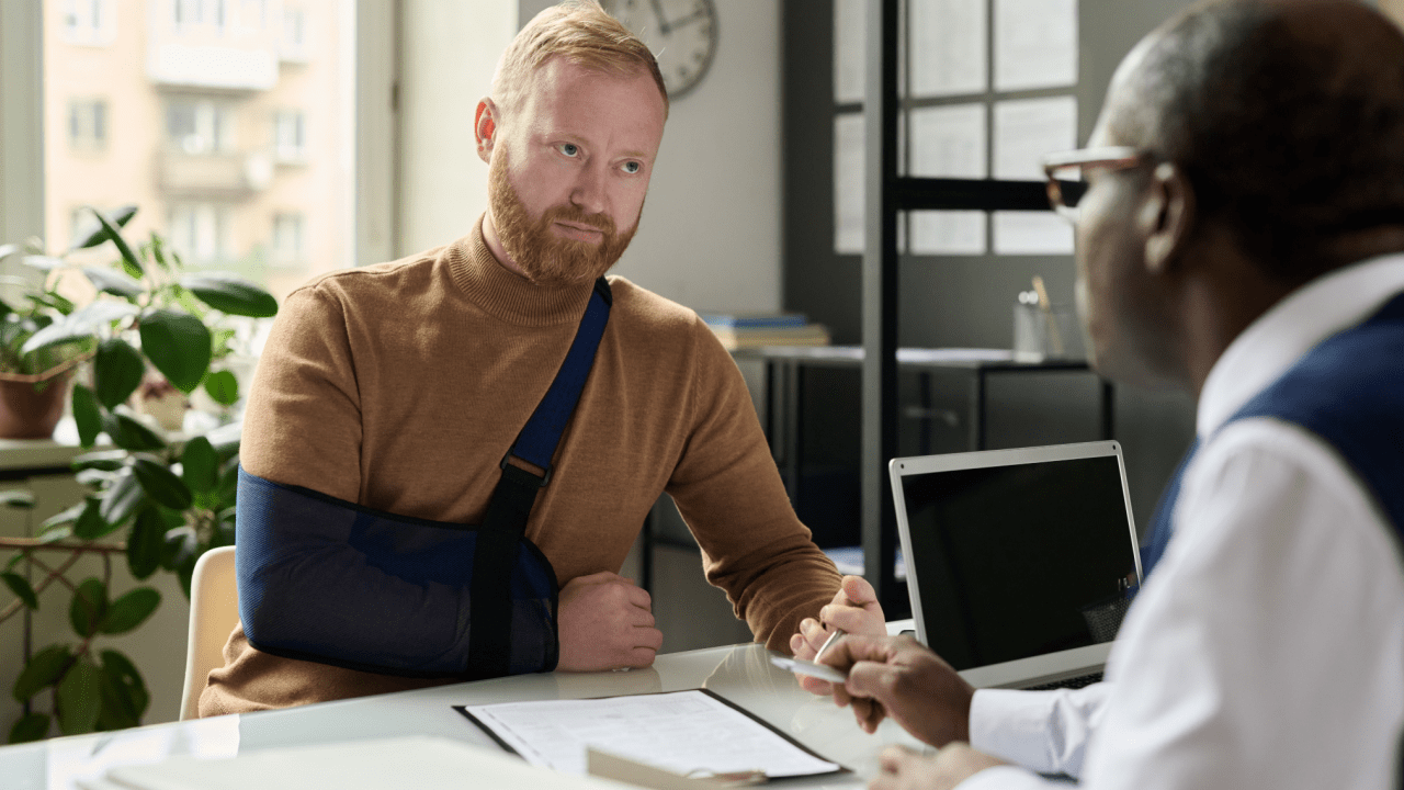 Injured man with arm sling meeting attorney about can you sue a trucking company for not having insurance legal case