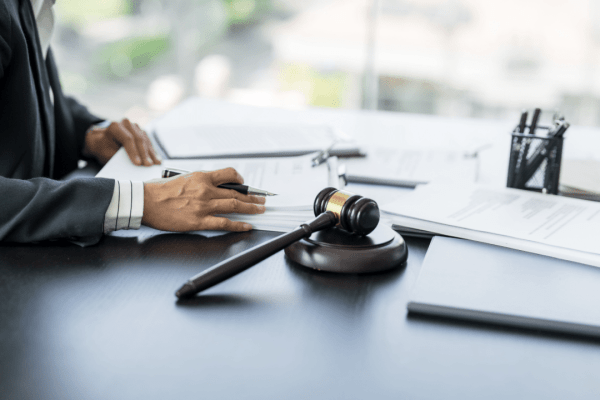 Lawyer in business suit reviewing legal documents at desk with gavel in professional law office