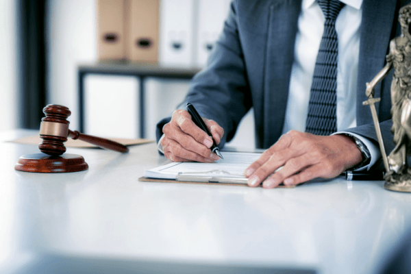 Professional attorney representing best lawyer for truck accident cases writing legal documents at desk with gavel and Lady Justice statue