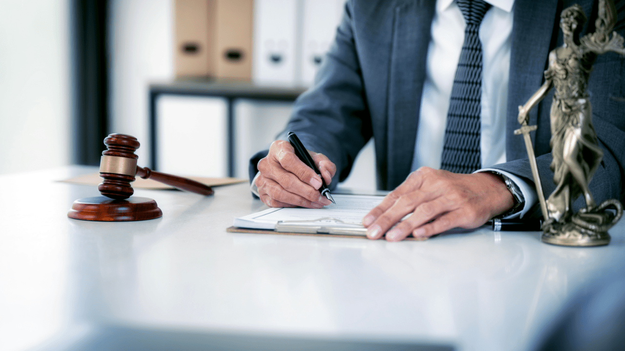 Professional attorney representing best lawyer for truck accident cases writing legal documents at desk with gavel and Lady Justice statue