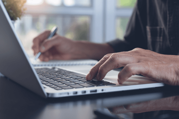 Professional researching costs and affordability of legal help while typing on laptop computer in office setting