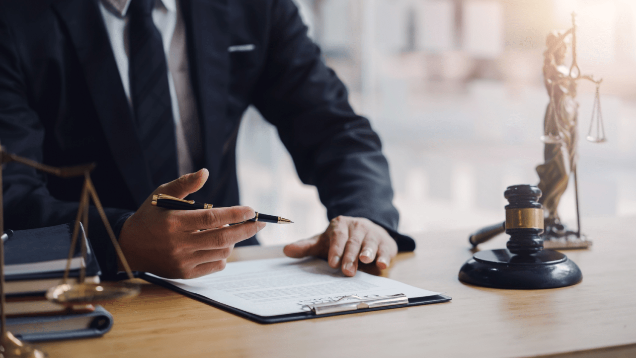 Lawyer reviewing truck accident settlements paperwork at desk with gavel and scales of justice