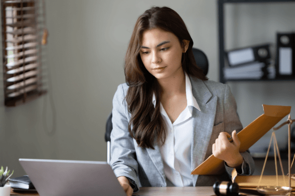 Female attorney reviewing legal documents to help clients understand should I ask an attorney how much my accident case is worth with scales of justice on desk