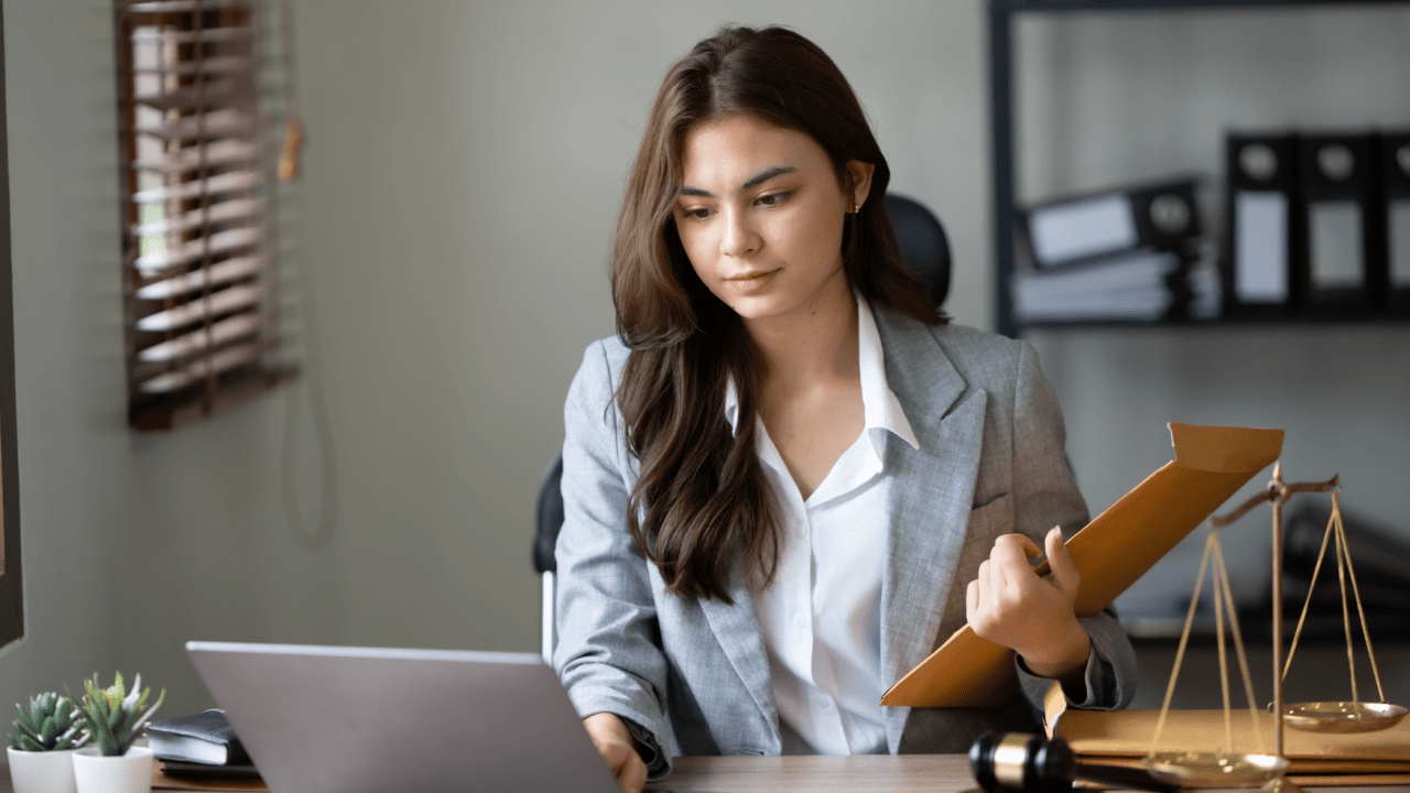 Female attorney reviewing legal documents to help clients understand should I ask an attorney how much my accident case is worth with scales of justice on desk