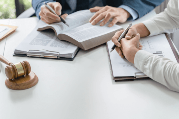 Lawyers reviewing legal documents and settlement terms with a gavel on the desk