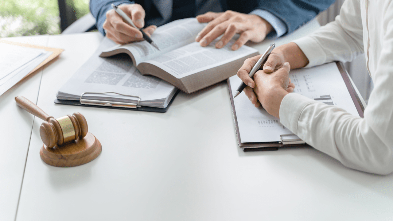 Lawyers reviewing legal documents and settlement terms with a gavel on the desk