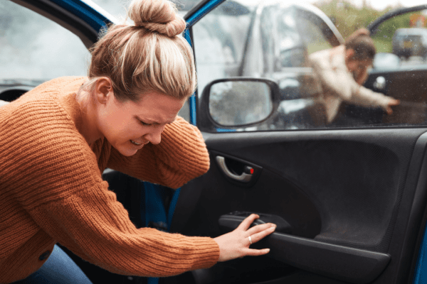 Woman examining vehicle damage after car accident while considering what kind of lawyer she needs for legal representation