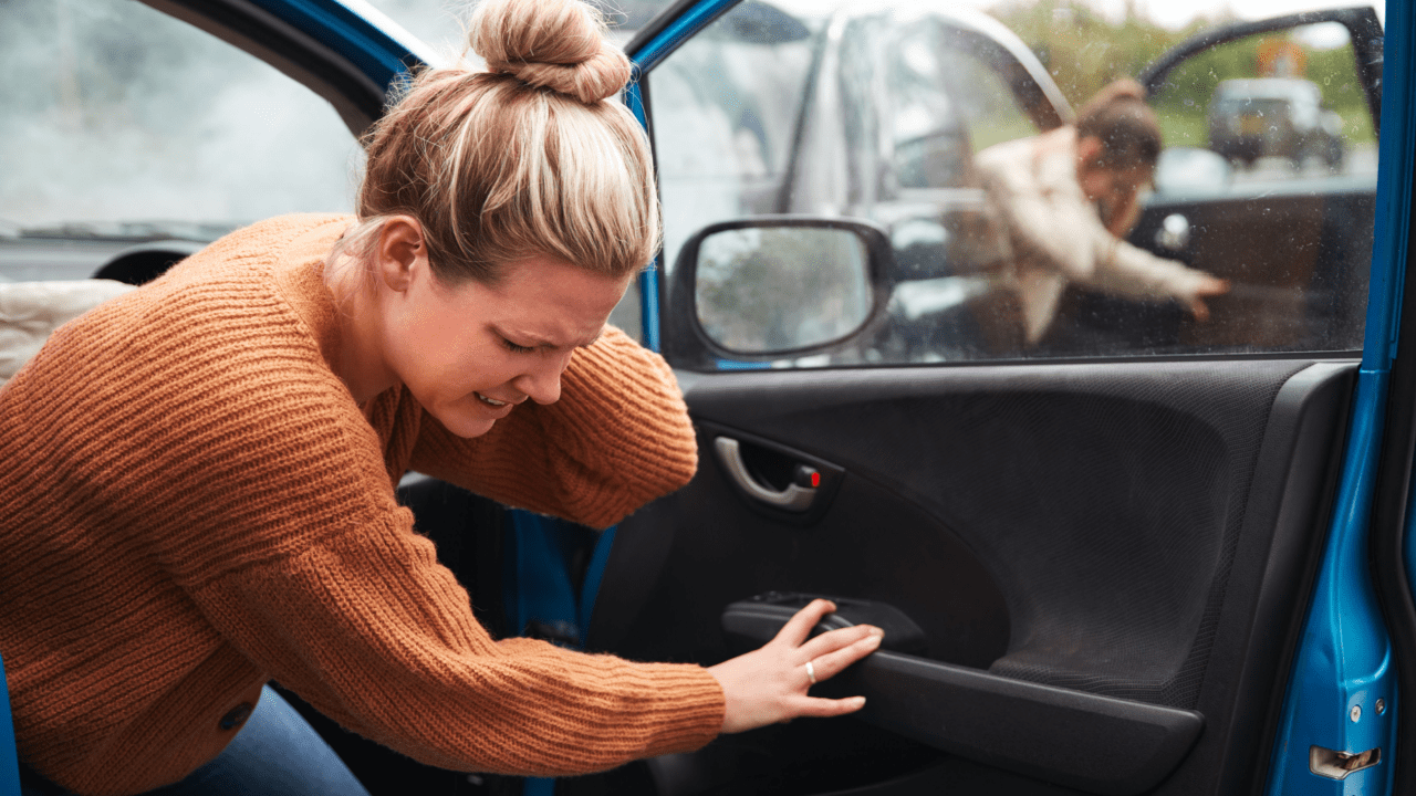 Woman examining vehicle damage after car accident while considering what kind of lawyer she needs for legal representation