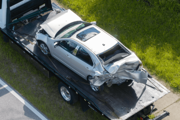 Damaged car on tow truck after accident showing how to sue someone for vehicle damage evidence