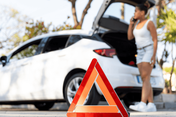 Emergency roadside triangle and woman calling for help - who to contact first after a truck accident emergency situation