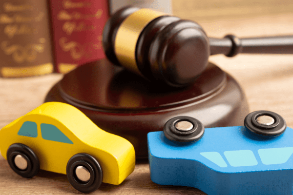 Toy cars positioned in front of judge's gavel and law books representing winning accident lawsuits and legal representation