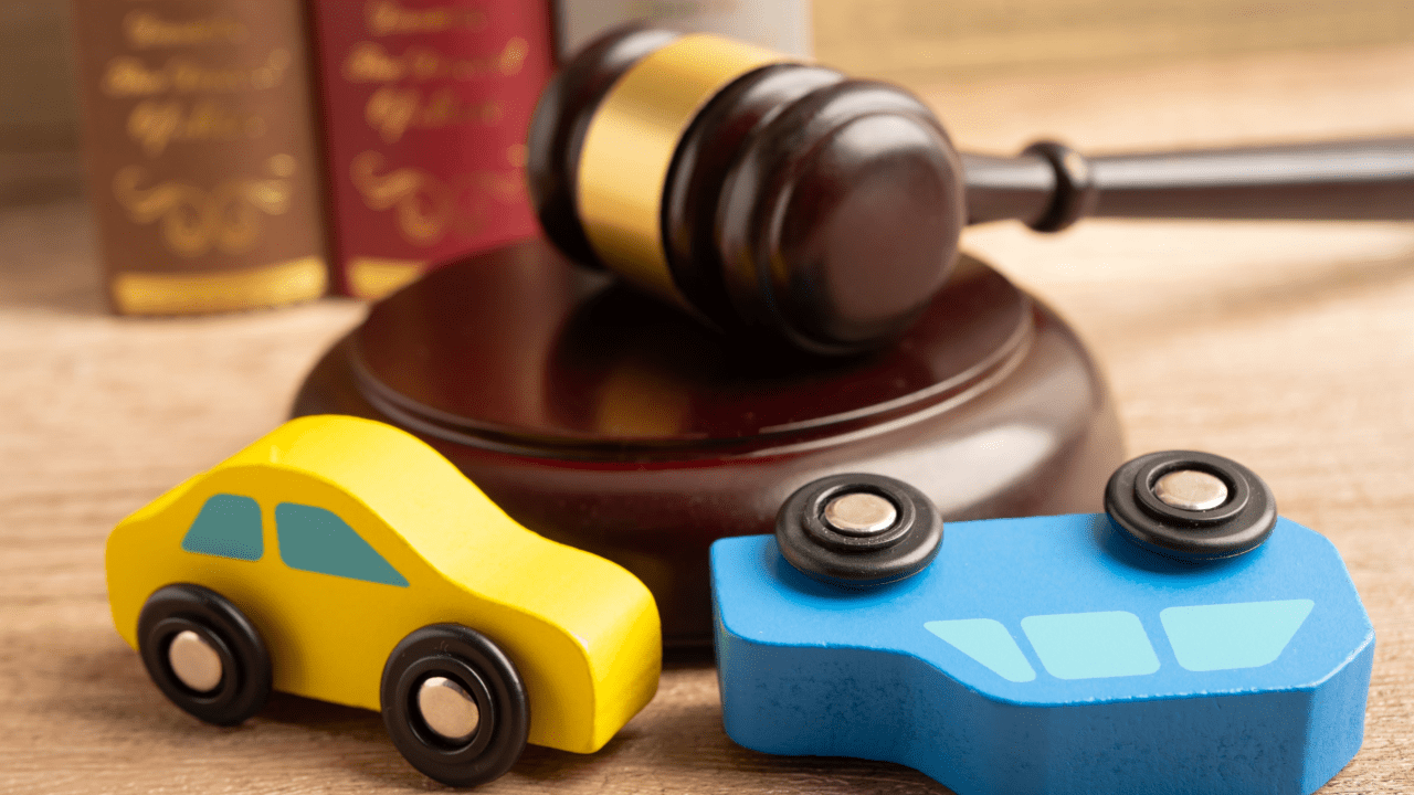 Toy cars positioned in front of judge's gavel and law books representing winning accident lawsuits and legal representation
