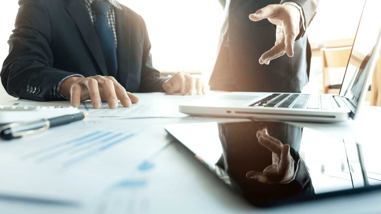 Business professionals discussing how do accident lawyers make money during legal consultation with laptop and financial documents