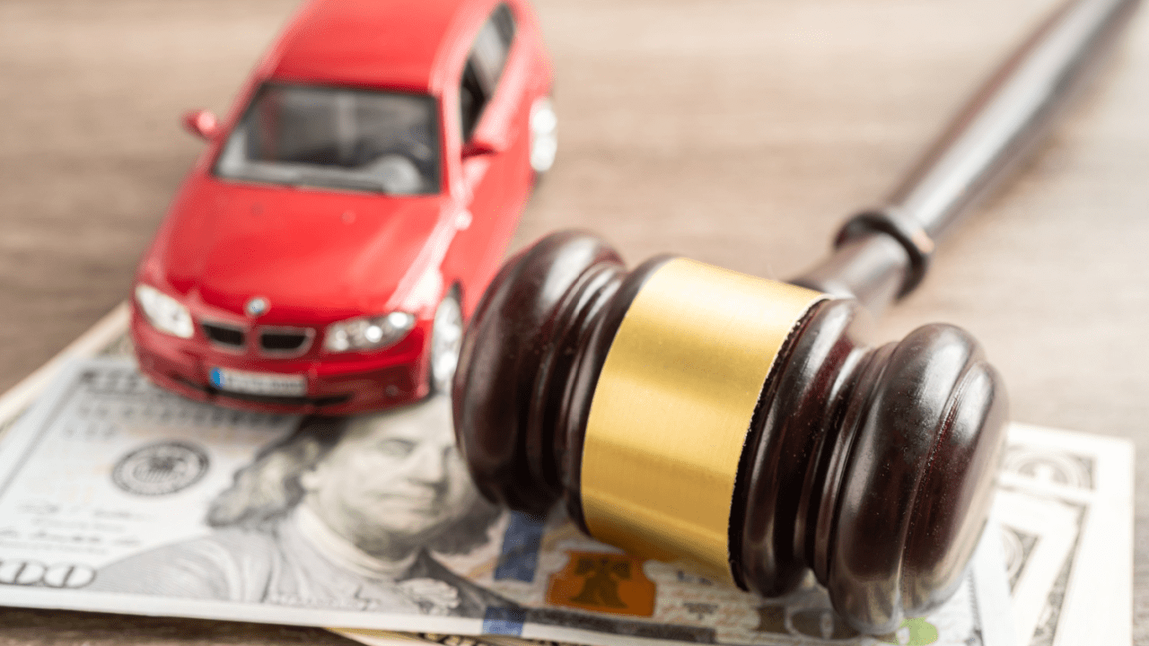 Red car model with wooden gavel and money representing how hard is it to win a car accident lawsui