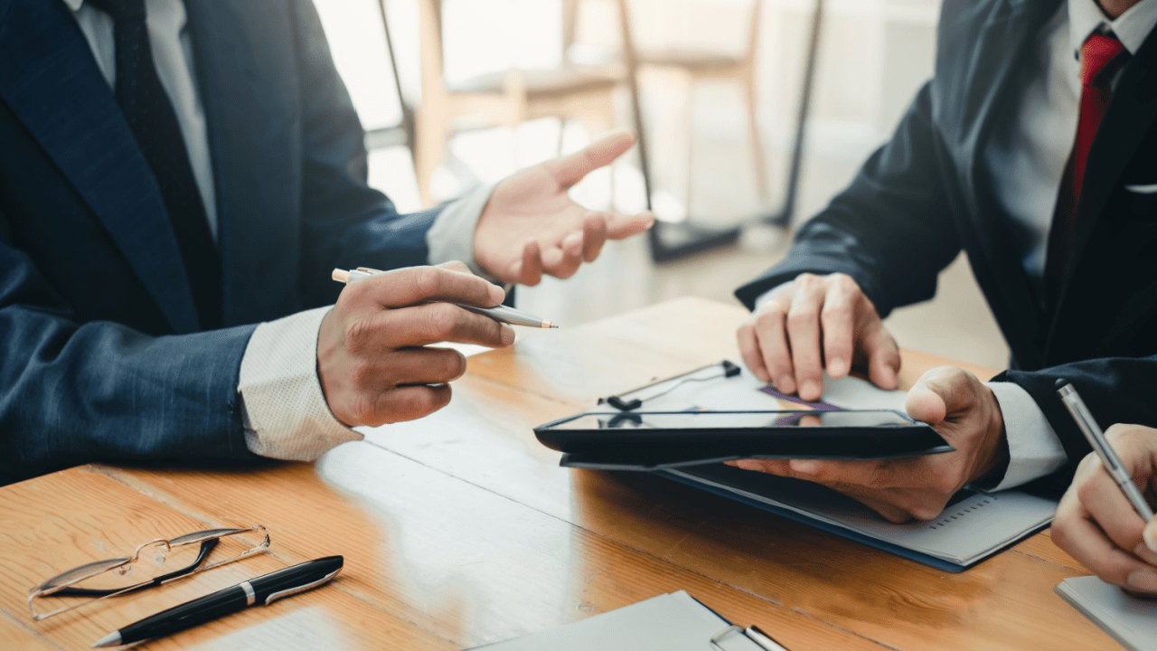 Lawyers and clients discussing how much of a 30k settlement will I get during legal consultation meeting with documents and tablets
