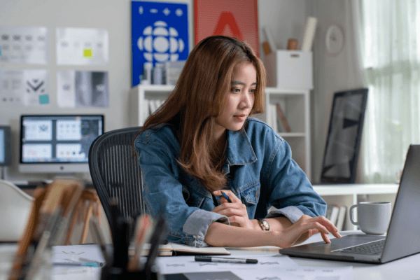 Professional woman researching truck crash compensation on laptop in modern office setting