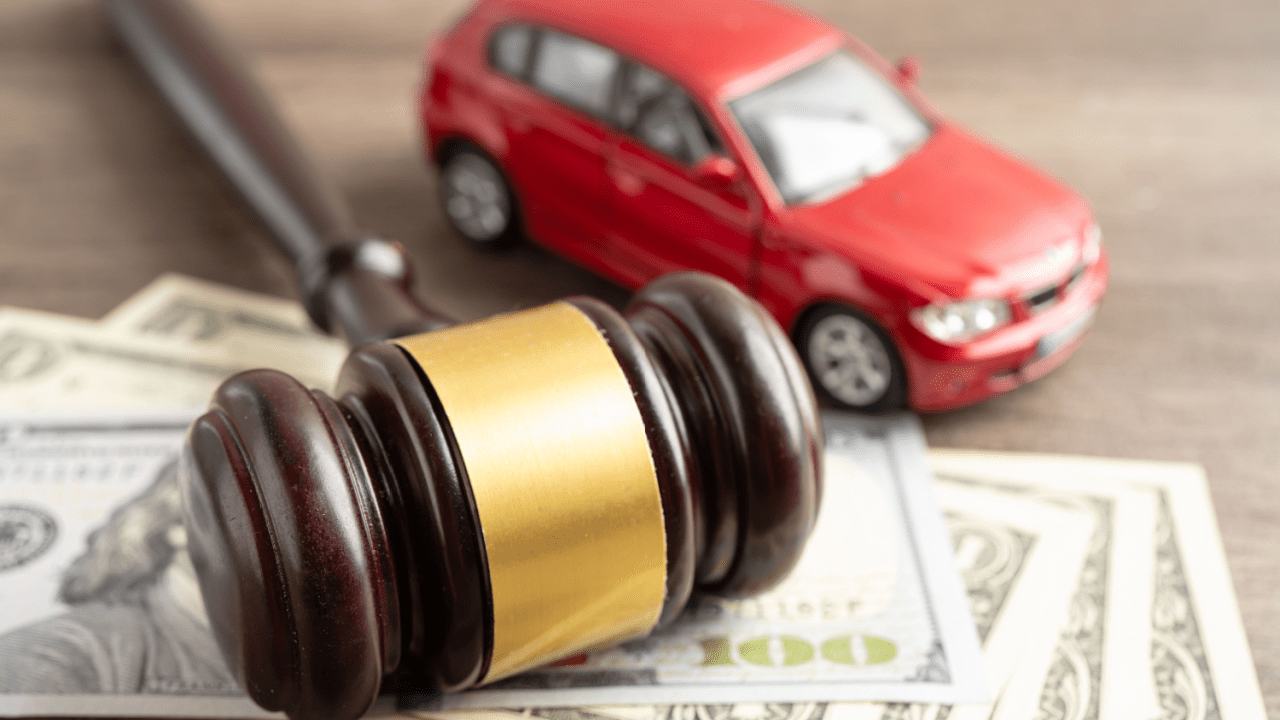Judge gavel with red car and money representing should I ask for more in a car accident lawsuit settlement negotiations