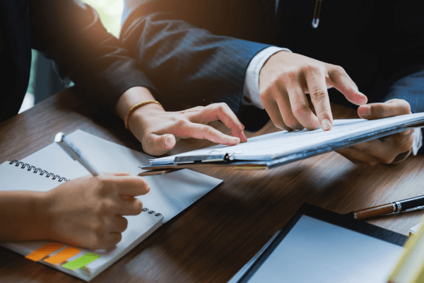 Business professionals discussing should I get a lawyer for a settlement while reviewing legal documents and using tablet technology