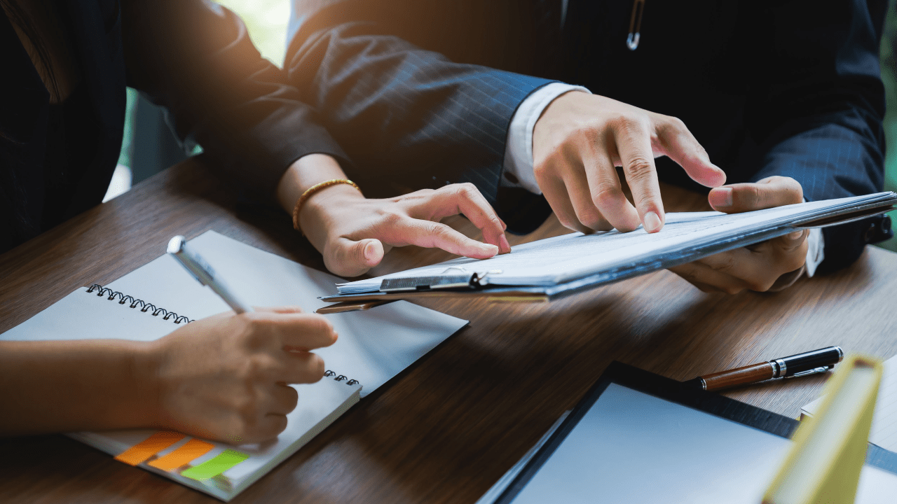 Business professionals discussing should I get a lawyer for a settlement while reviewing legal documents and using tablet technology