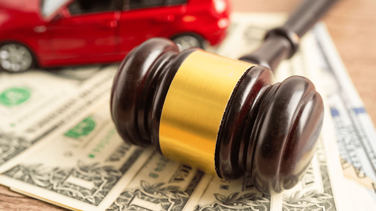 Legal gavel on dollar bills with red car representing what percentage of car accident cases go to trial and settlement decisions