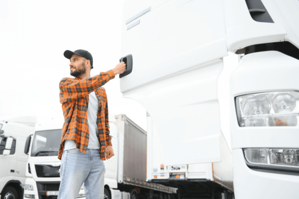 Professional truck driver standing next to commercial trucks discussing what is the insurance for truck drivers injury coverage
