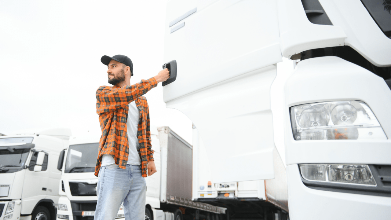 Professional truck driver standing next to commercial trucks discussing what is the insurance for truck drivers injury coverage
