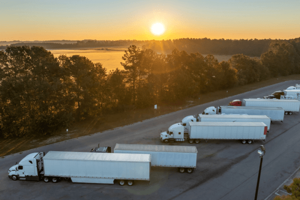 Commercial trucks parked at rest stop illustrating can DOT fine a company for safety violations