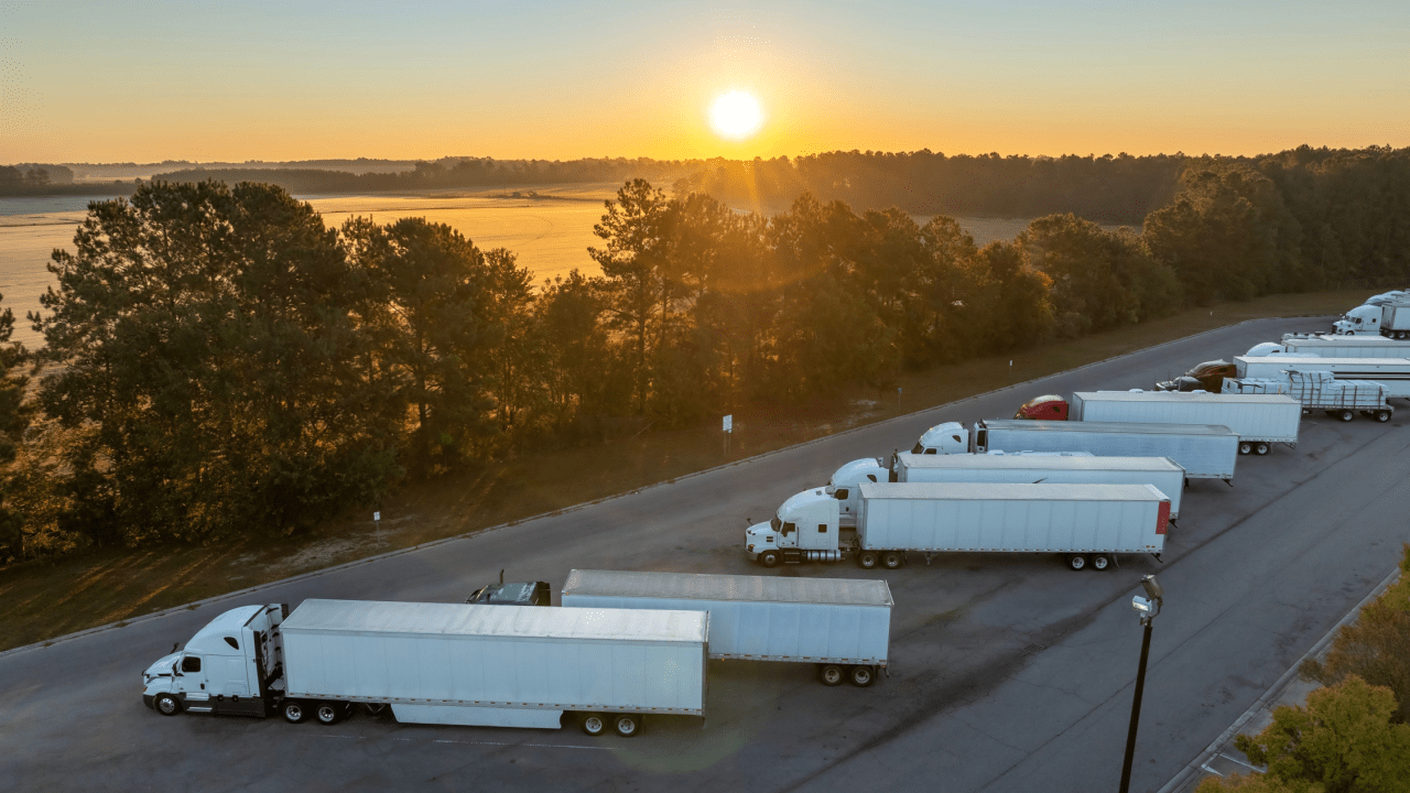Commercial trucks parked at rest stop illustrating can DOT fine a company for safety violations