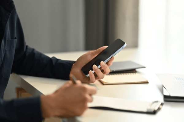 Professional using smartphone to research how does insurance affect settlements while reviewing legal documents at desk