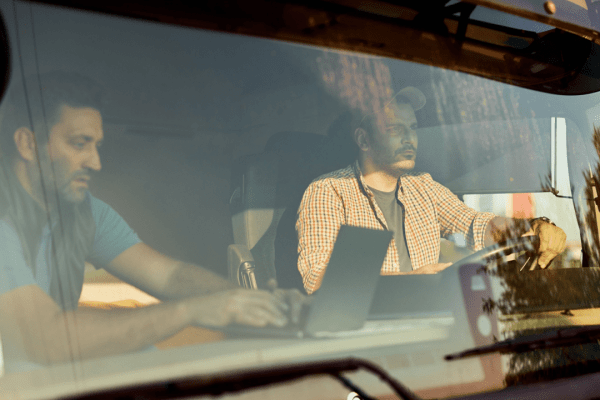 Commercial truck drivers discussing how long do DOT violations stay on your record inside semi-truck cab
