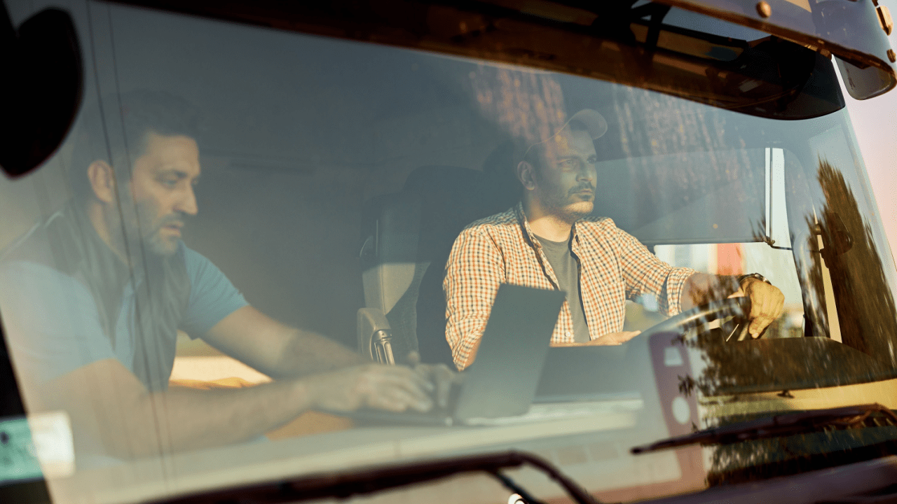 Commercial truck drivers discussing how long do DOT violations stay on your record inside semi-truck cab