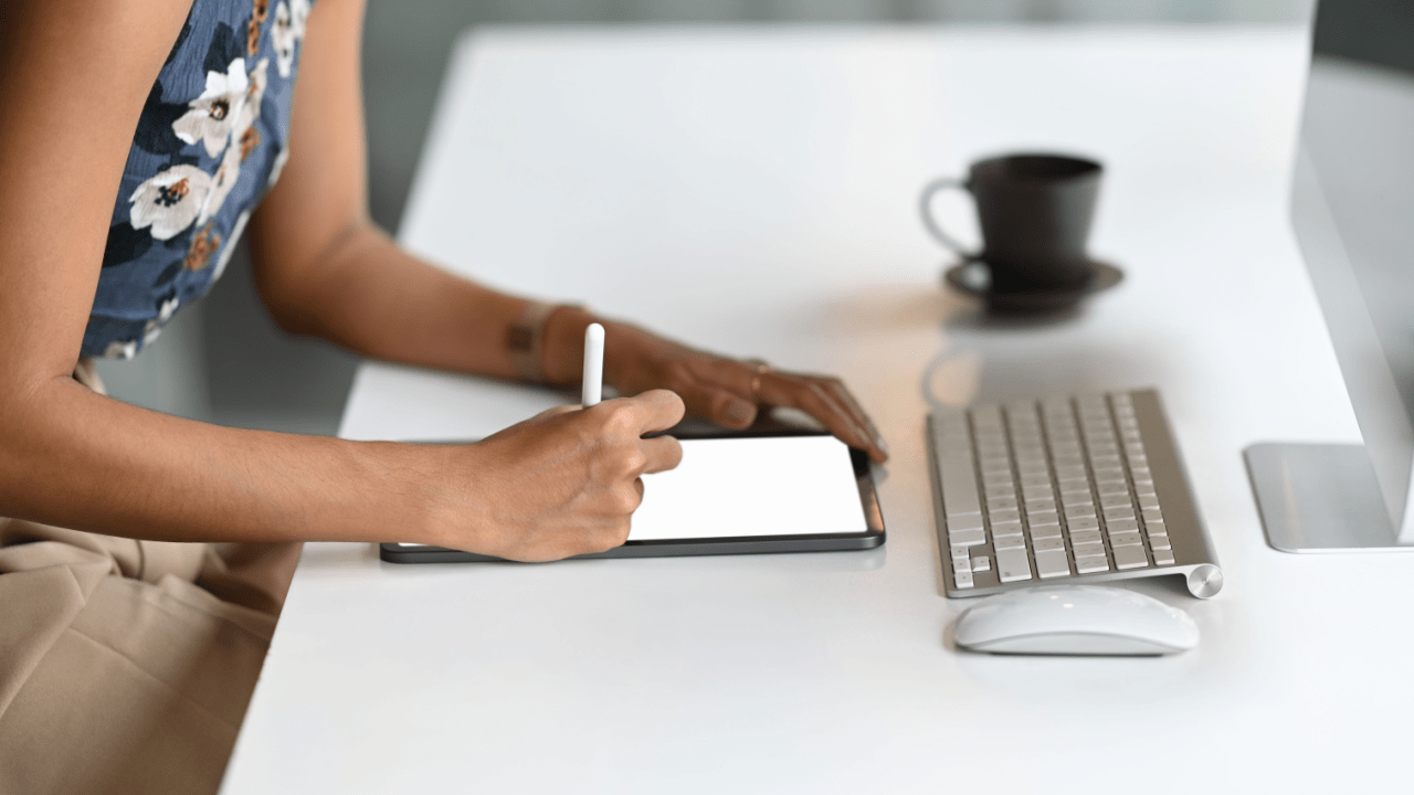 Woman using stylus on tablet to research how to negotiate with trucking insurance companies at modern workspace