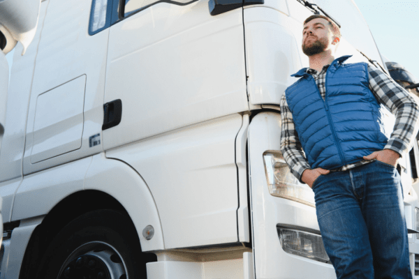 Professional truck driver standing by commercial truck understanding truck driver hours of service regulations