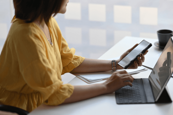 Woman researching what injuries lead to higher settlement payouts using laptop and smartphone at office desk